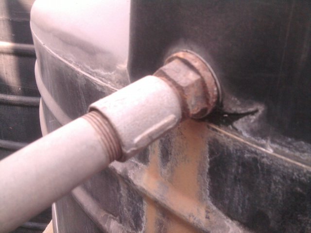 A closeup of the cracks in the tank areound the pipe.